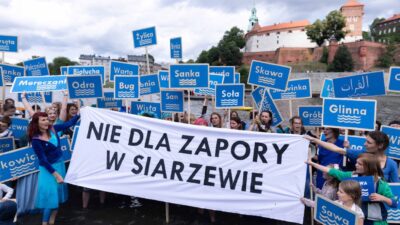 Protest przeciw budowie zapory w Siarzewie – uczestnicy stoją w wodzie z tablicami nazw polskich rzek