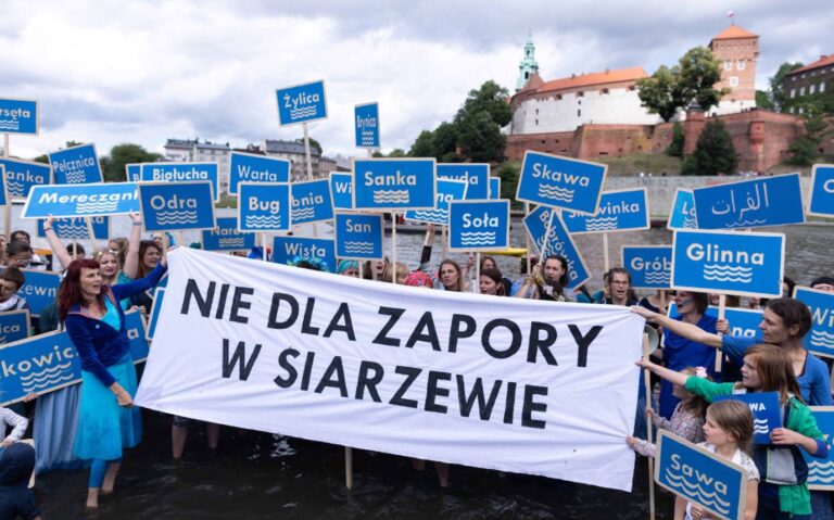 Protest przeciw budowie zapory w Siarzewie – uczestnicy stoją w wodzie z tablicami nazw polskich rzek