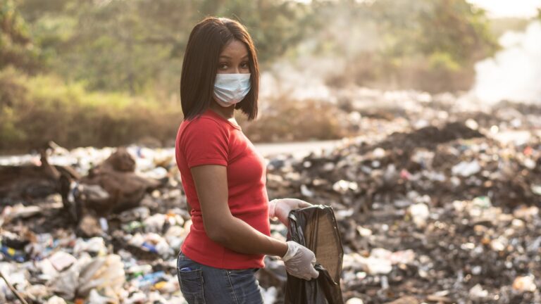 Black woman cleaning up a polluted dump site