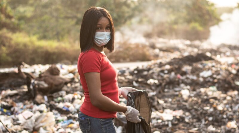Black woman cleaning up a polluted dump site